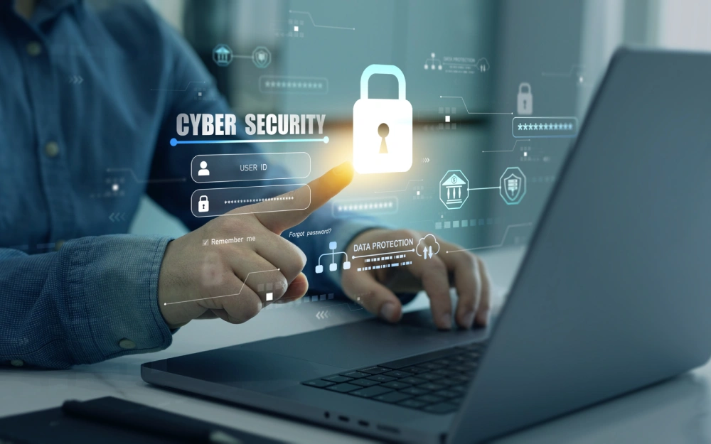 Person interacting with a cybersecurity digital interface and laptop.
