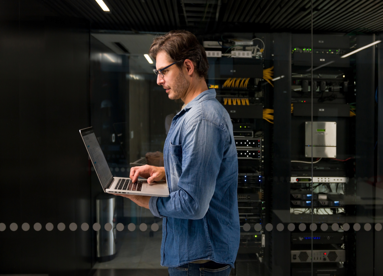 Man working on laptop in server room
