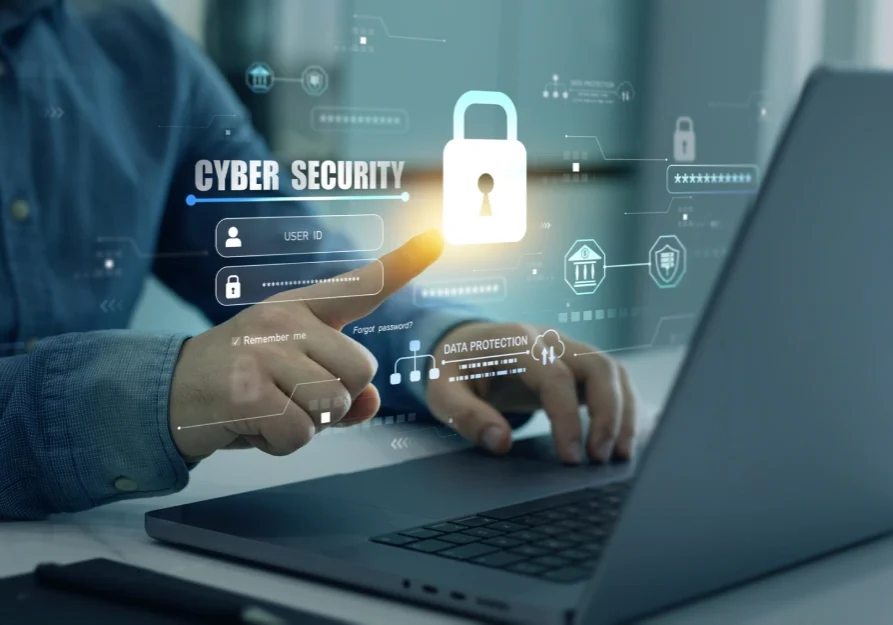 Person interacting with a cybersecurity digital interface and laptop.