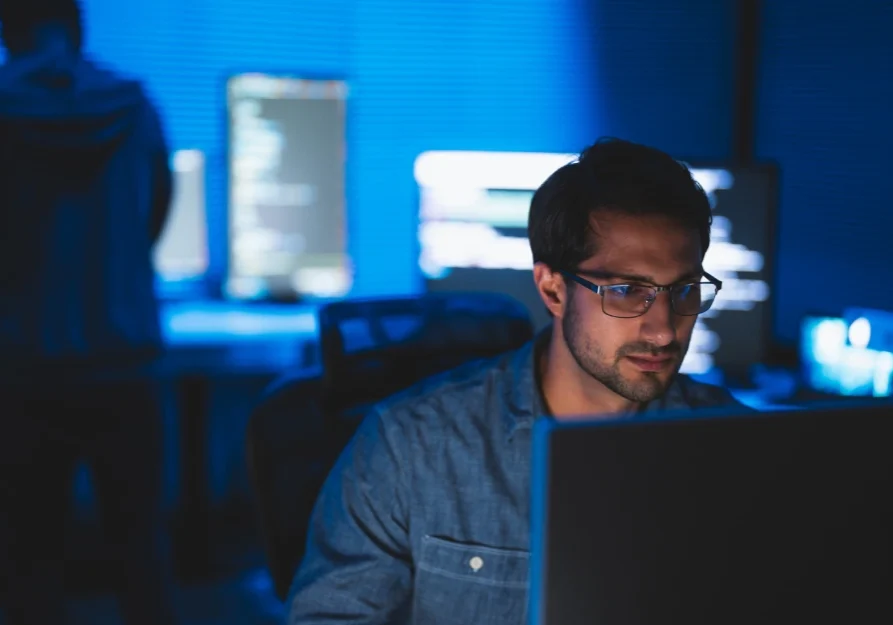 Man working late on a computer in a dark office.